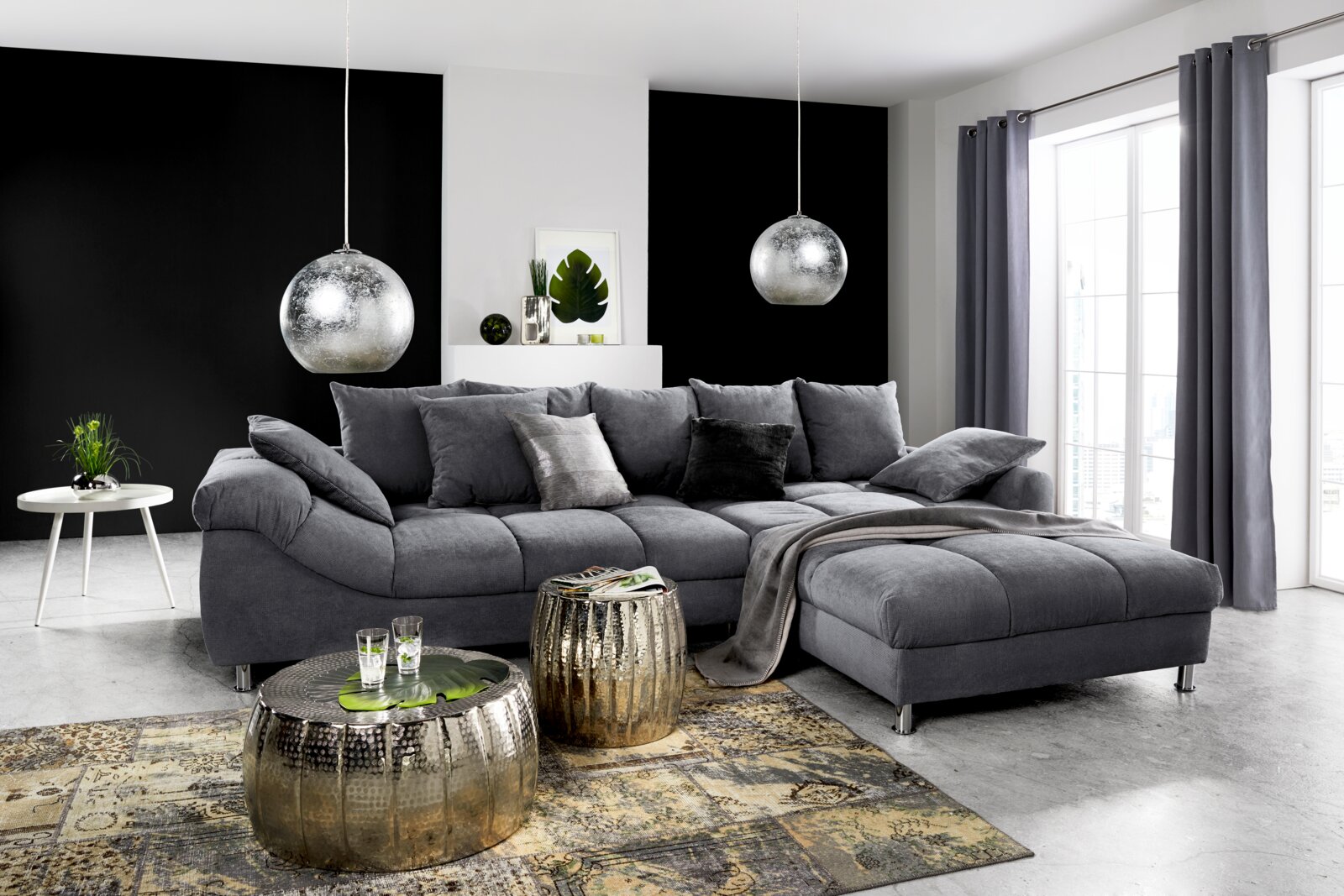 Graue Rundecke (L) in einem modernen Wohnzimmer, seitliche Perspektive, mit dekorativen Kissen und Decke, umgeben von stilvollen Möbeln und großen Fenstern.
