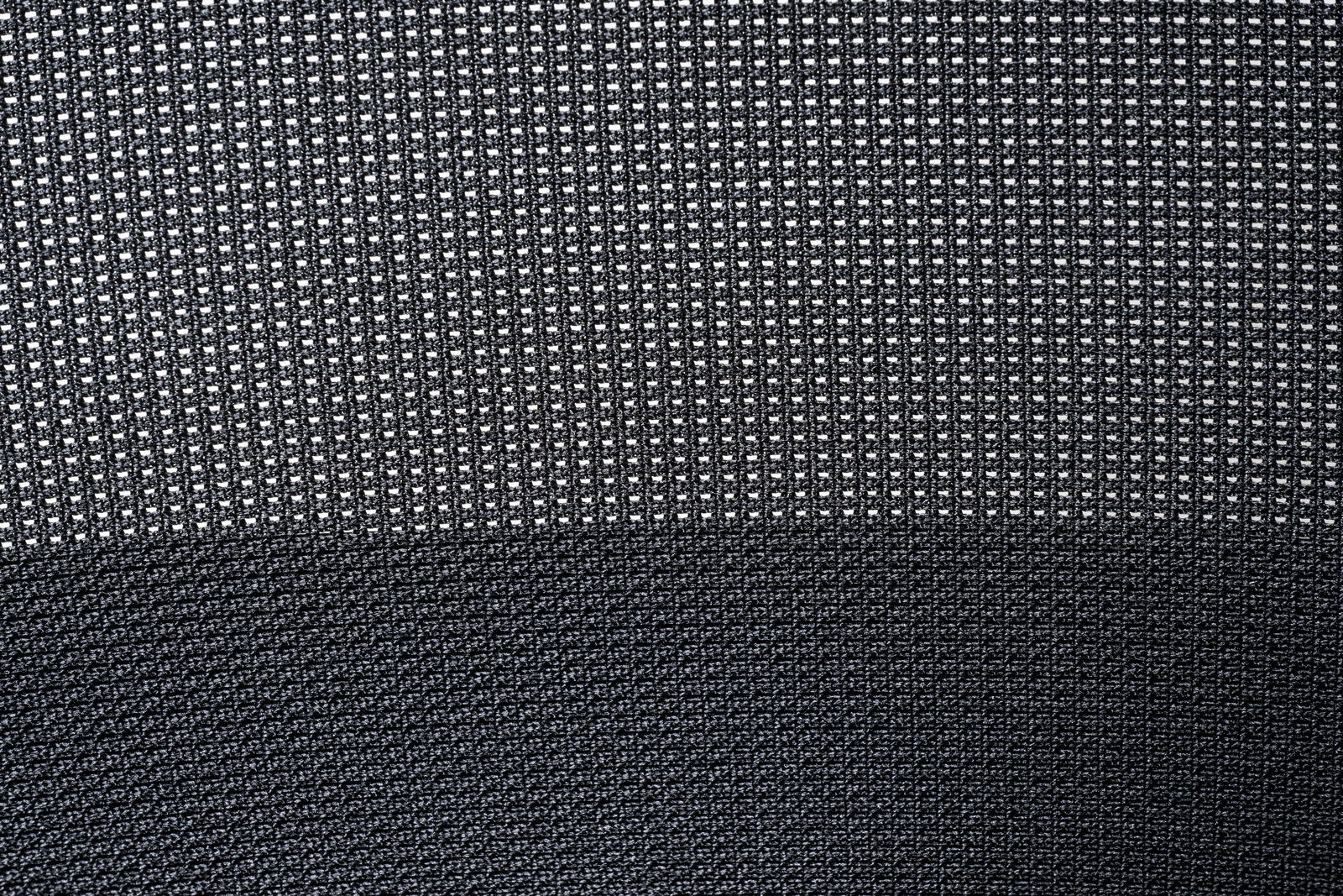 Nahaufnahme des Stoffmusters eines Besucherstuhls in dunklen Tönen, von oben betrachtet.