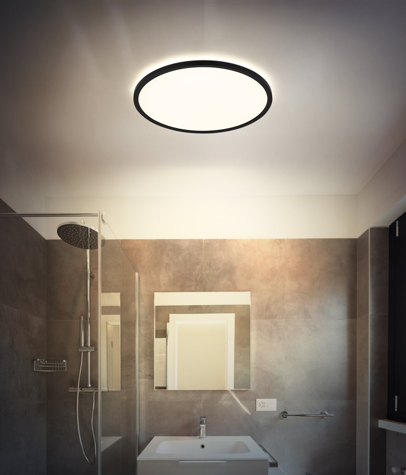 Runde, flache LED-Deckenleuchte mit schwarzem Rahmen und warmweißem Licht in modernem Badezimmer; Aufnahme aus leicht nach oben gerichteter Perspektive auf die Decke.