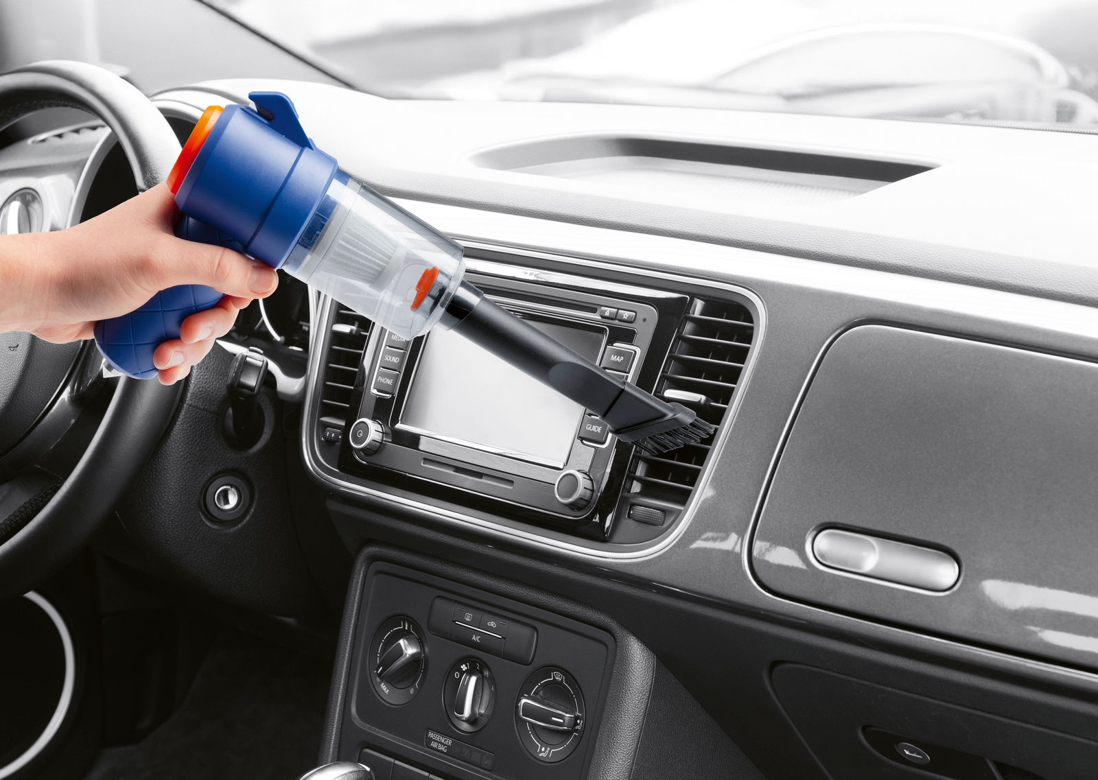 Handstaubsauger in der Hand, der das Armaturenbrett eines Autos aus der Innenperspektive reinigt