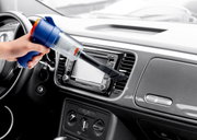 Handstaubsauger in der Hand, der das Armaturenbrett eines Autos aus der Innenperspektive reinigt