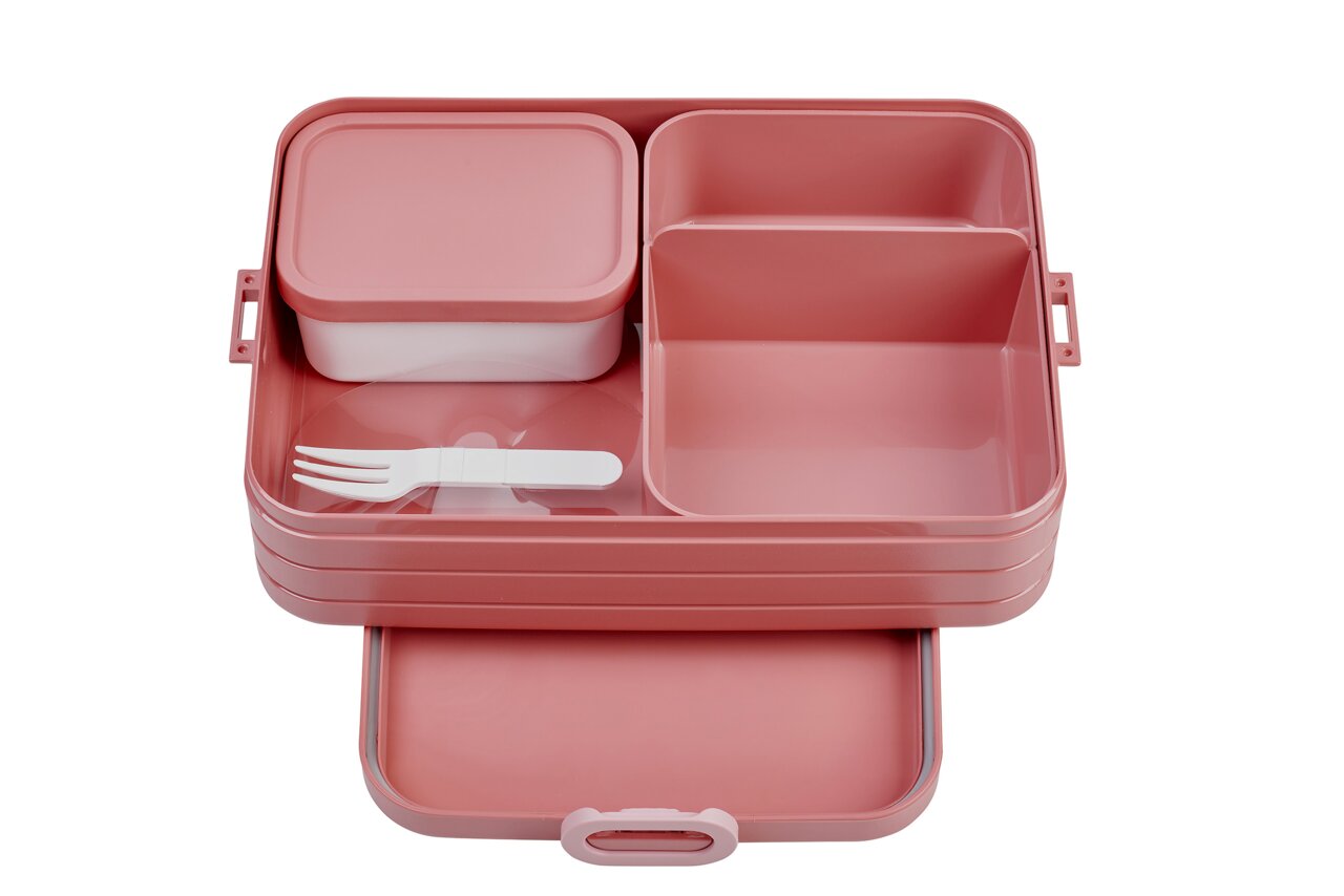 Rosa Bento-Lunchbox mit mehreren Fächern und einem weißen Besteck, von oben betrachtet.