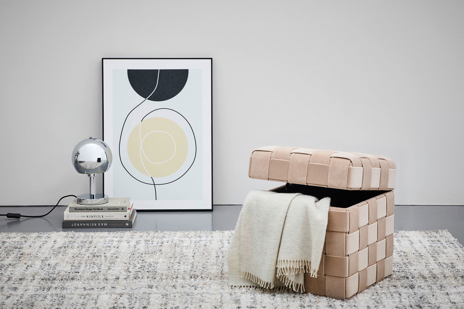 Hocker mit Stauraum in beige, geöffnet mit einer Decke darin, seitliche Perspektive