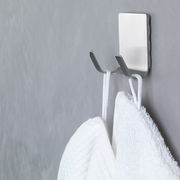 Nahaufnahme eines an der Wand befestigten, wasserfesten tesa Powerstrips Hakens mit zwei Handtüchern.