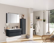 Moderner Badezimmer-Mittelschrank in dunklem Holz, rechts an der Wand montiert, mit seitlicher Perspektive.