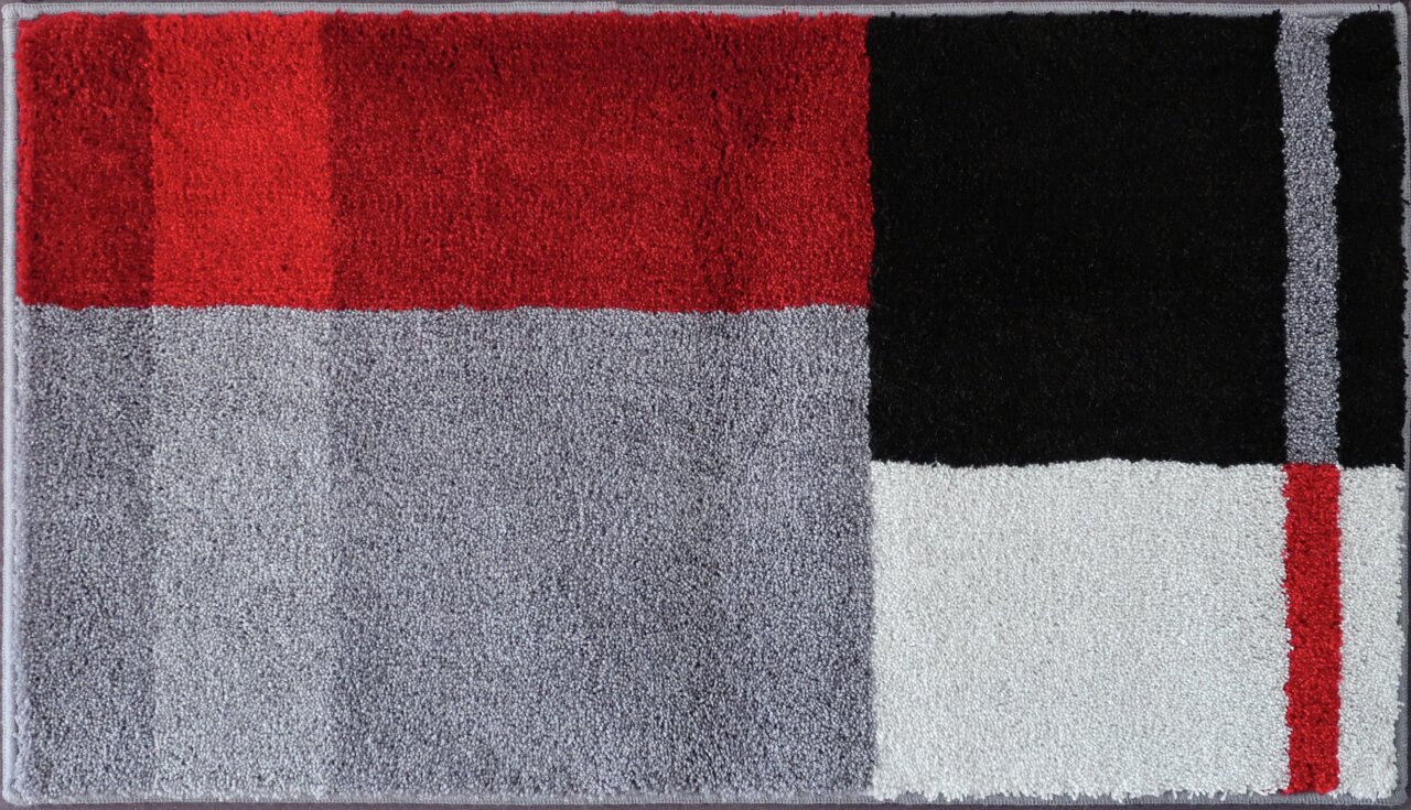 Badteppich in rechteckiger Form mit einem modernen geometrischen Muster in Rot, Schwarz, Grau und Weiß, aus der Vogelperspektive fotografiert.