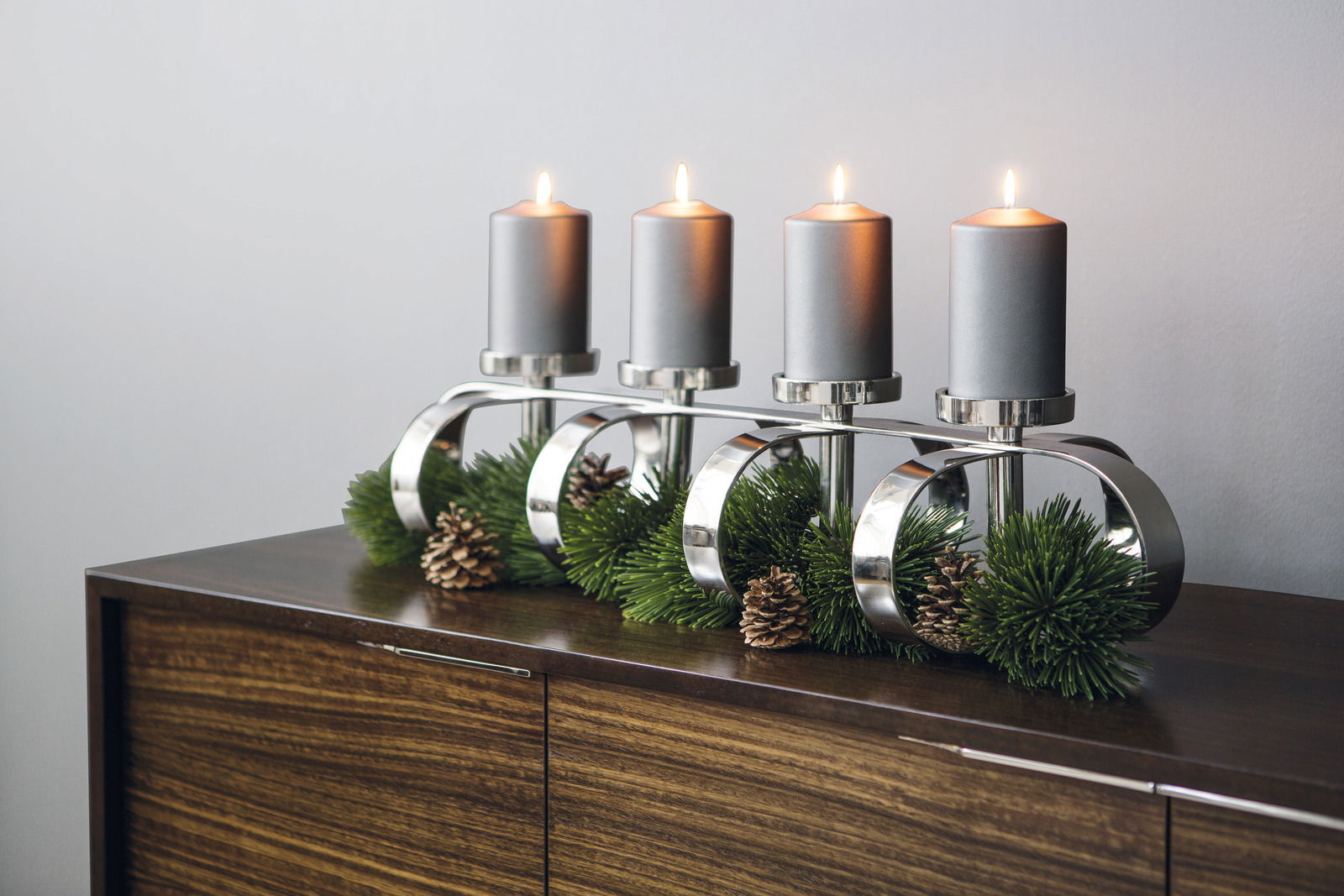Fink Leuchter 4-flg. GORDEN 85cm Vierflammiger GORDEN Leuchter mit silbernem Gestell, grauen Kerzen und dekorativen Tannenzweigen und Zapfen, seitliche Perspektive.