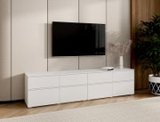 Modernes weißes Lowboard/TV-Board mit glatter Front und mehreren Fächern unter einem wandmontierten Flachbildfernseher im Wohnzimmer, Ansicht frontal mit leichter Perspektive von links.