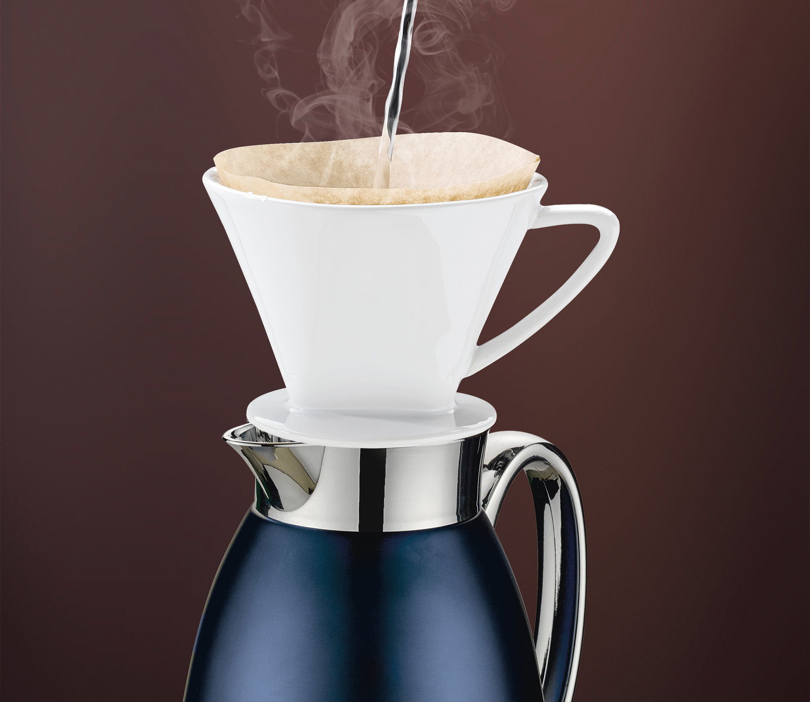 Isolierkanne Venezia in tiefem Blau mit einem weißen Kaffeefilteraufsatz, aus dem heißes Wasser dampft, seitliche Perspektive