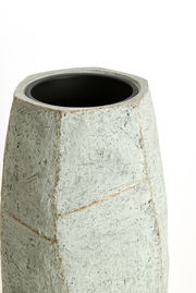 Moderner, geometrisch geformter Topf aus grauem Material, Ansicht von schräg oben.