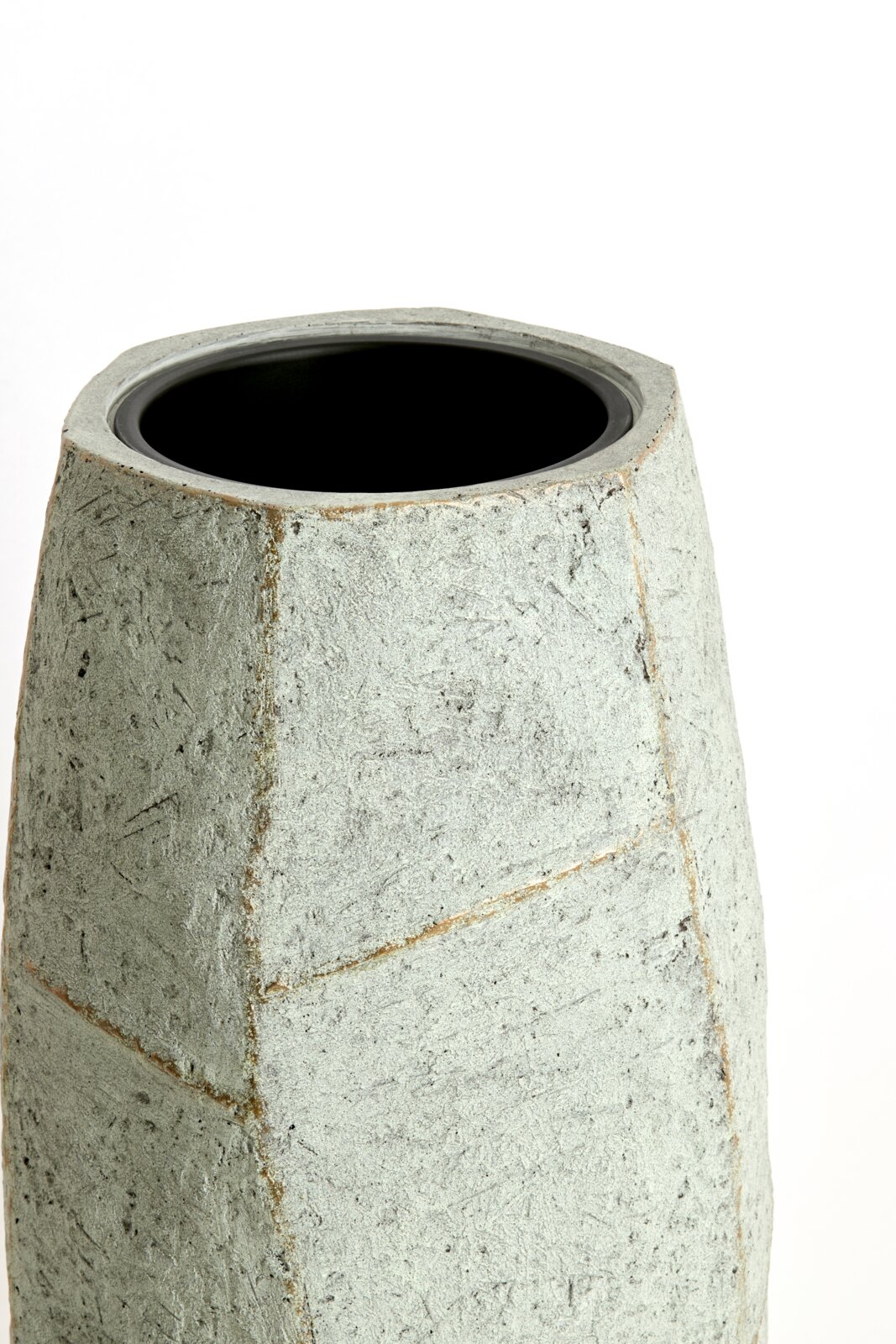 Moderner, geometrisch geformter Topf aus grauem Material, Ansicht von schräg oben.