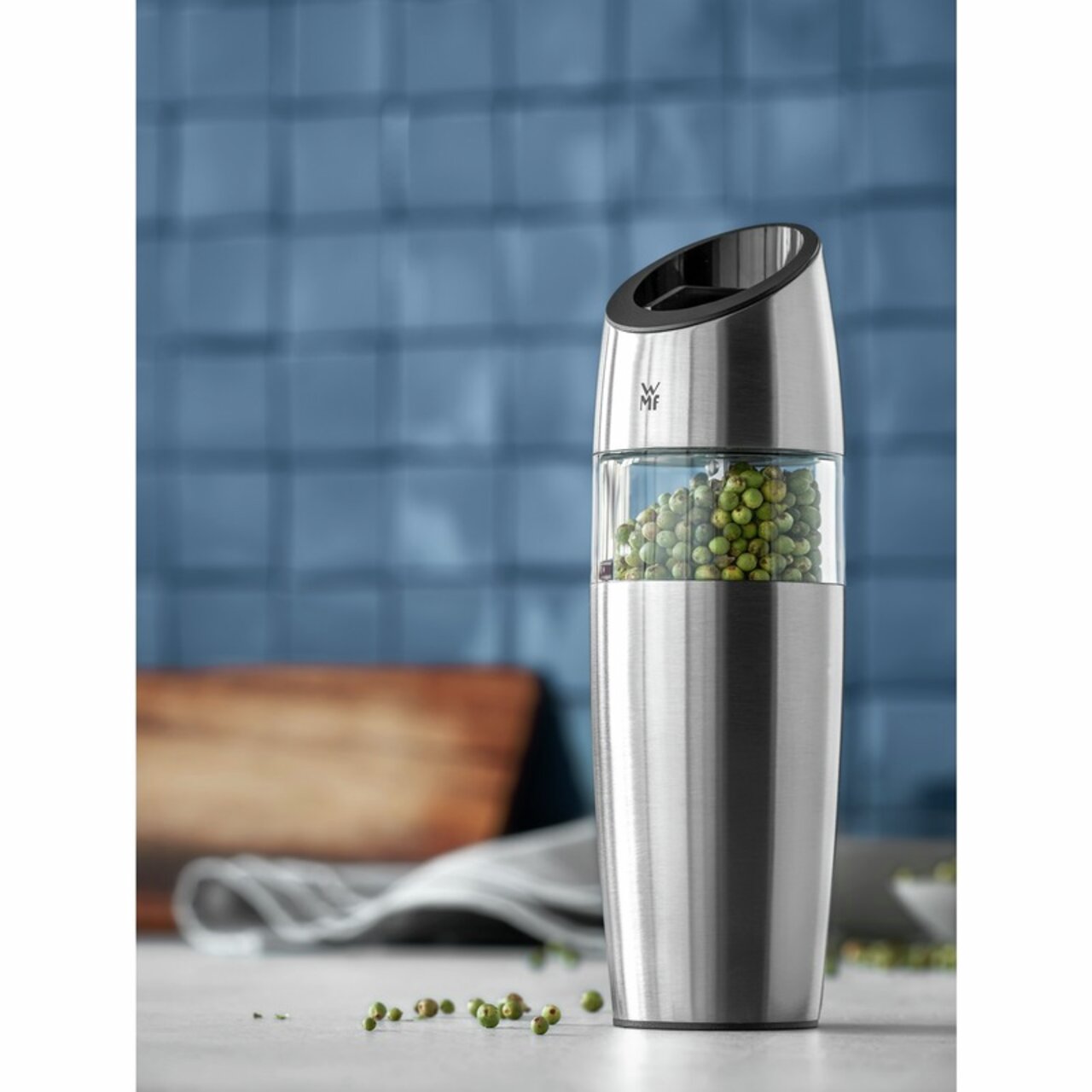 Elektrische Mühle aus Edelstahl mit transparentem Behälter, gefüllt mit grünen Pfefferkörnern, seitliche Perspektive