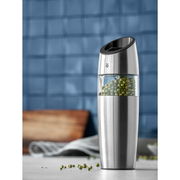 Elektrische Mühle aus Edelstahl mit transparentem Behälter, gefüllt mit grünen Pfefferkörnern, seitliche Perspektive