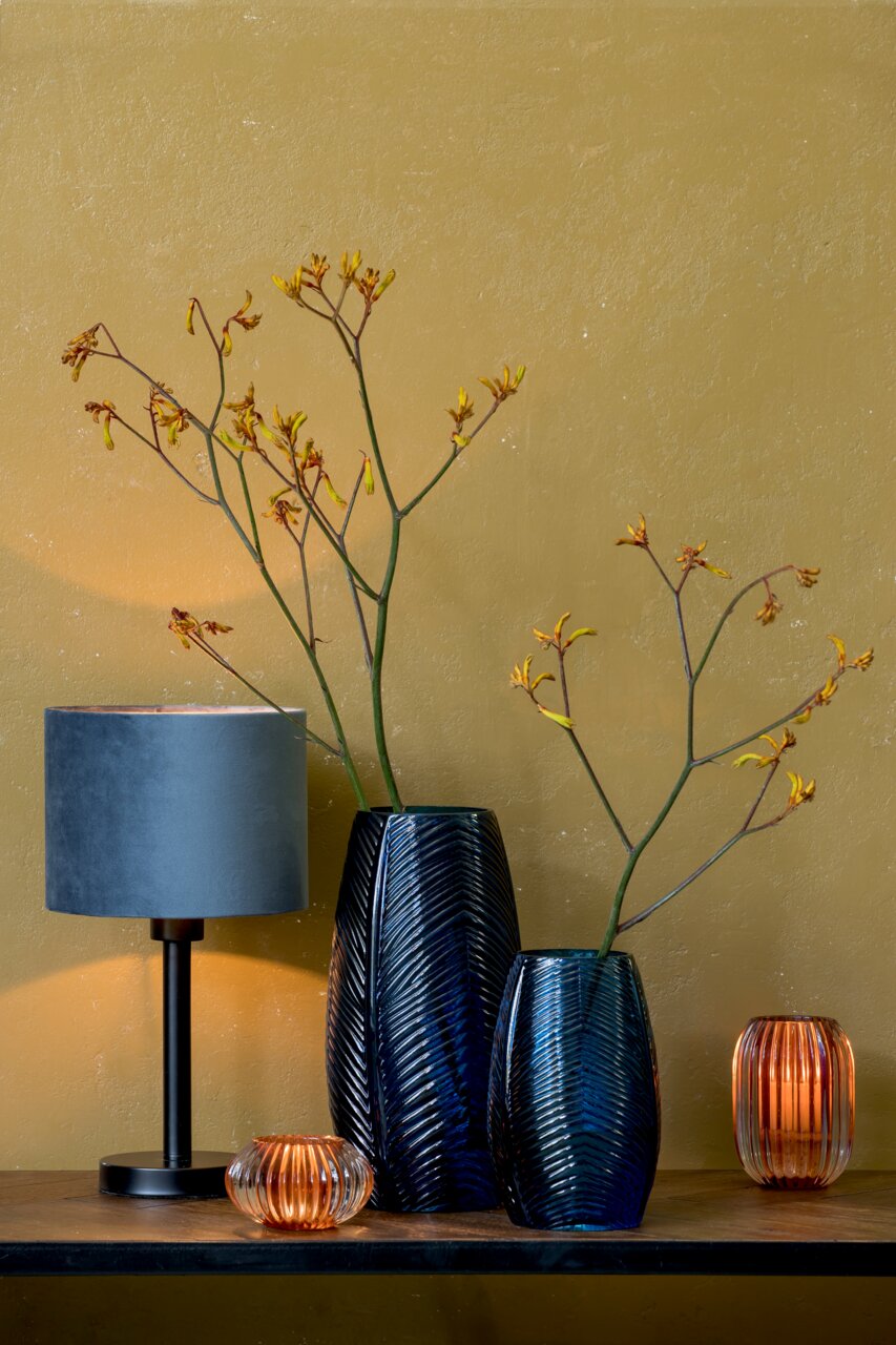 Light&Living Lampenfuß WASHINGTON Moderner Lampenfuß in Schwarz mit blauem Lampenschirm, seitliche Perspektive, umgeben von dekorativen Vasen und Kerzenhaltern auf einem Holztisch vor einer senfgelben Wand.