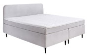 Boxspringbed in zijaanzicht met een lichtgrijze stoffen bekleding en zwarte poten