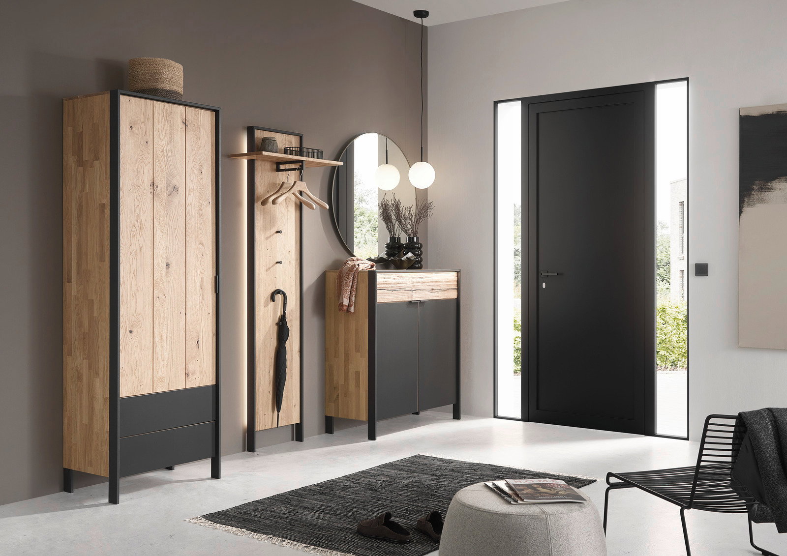 Moderne Garderobeneinrichtung mit Holz- und Metallelementen, bestehend aus einem hohen Schrank, einem Garderobenpaneel mit Haken und einem runden Spiegel, aus der Perspektive des Eingangsbereichs betrachtet.