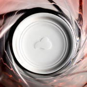 Blick von oben in ein rotes Trinkglas Twist mit spiralförmigem Design und weißem Boden.