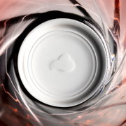 Blick von oben in ein rotes Trinkglas Twist mit spiralförmigem Design und weißem Boden.