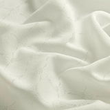 Nahaufnahme eines weißen Vorhangstoffs mit dezentem Muster und weicher Textur.