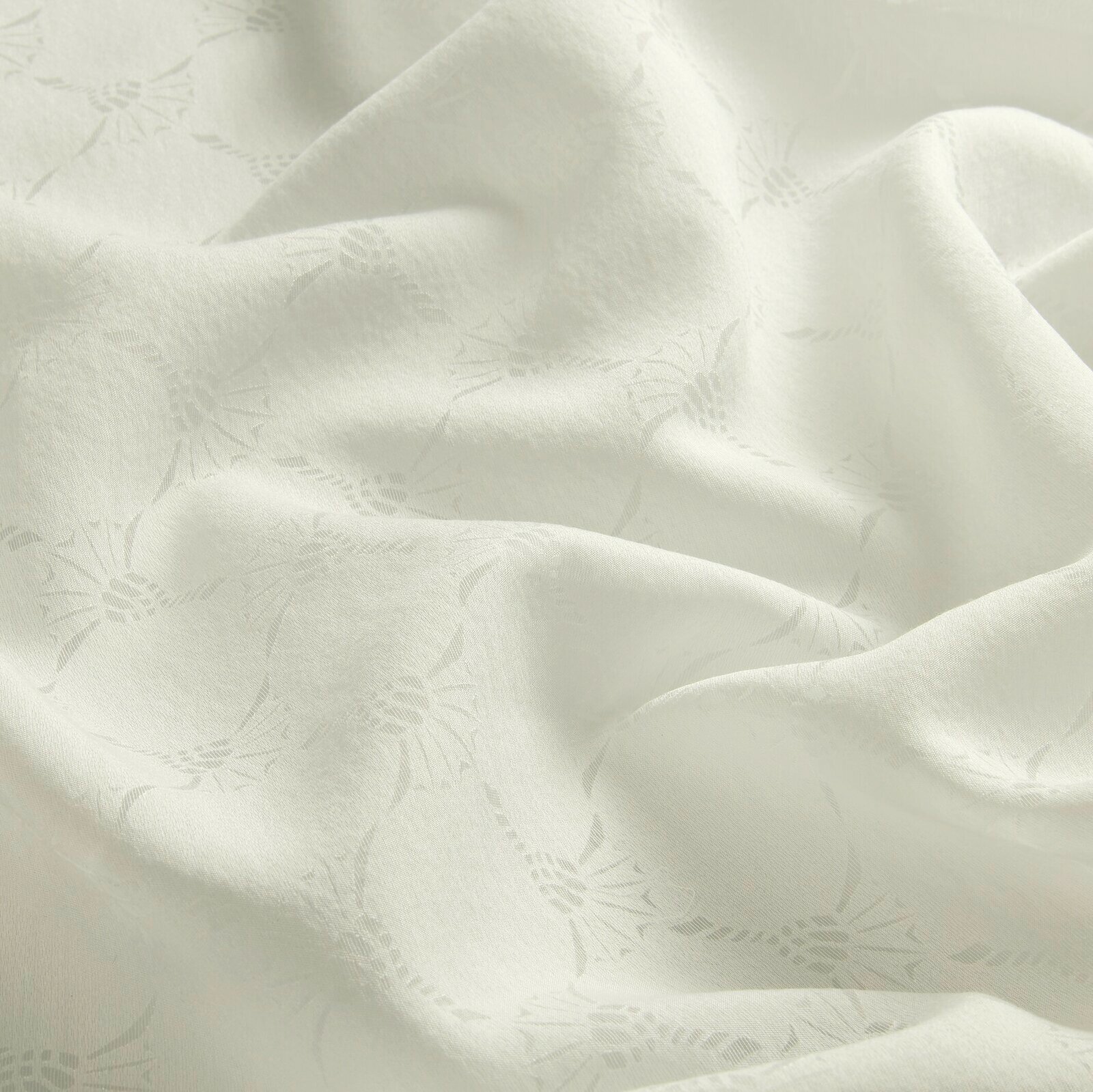 Nahaufnahme eines weißen Vorhangstoffs mit dezentem Muster und weicher Textur.