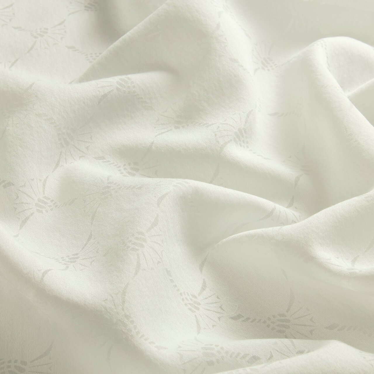 Nahaufnahme eines weißen Vorhangstoffs mit dezentem Muster und weicher Textur.