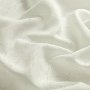 Nahaufnahme eines weißen Vorhangstoffs mit dezentem Muster und weicher Textur.