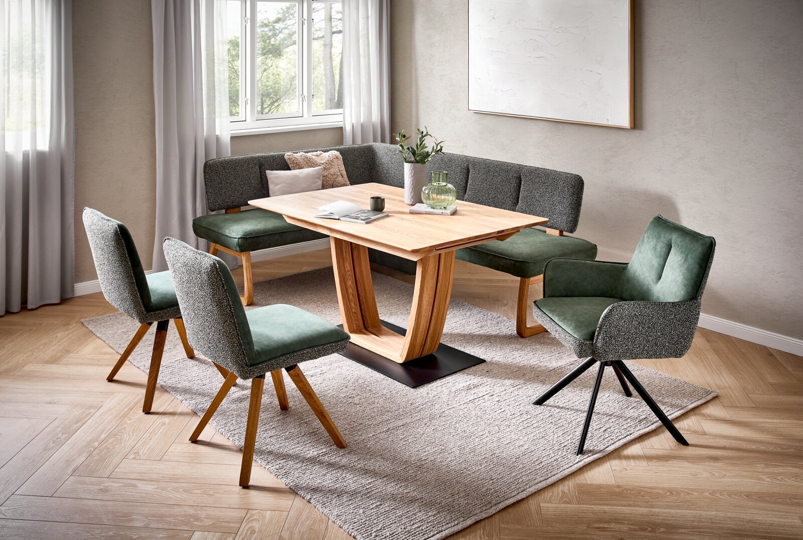 Venda Stuhl BLUE SEA Moderne Essgruppe im skandinavischen Stil mit rechteckigem Holztisch auf schwarzem Sockel, Eckbank mit grünen Sitzpolstern und grauer Rückenlehne sowie zwei Stühlen und einem Drehstuhl; aufgenommen in schräger Perspektive von vorne links.