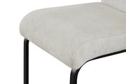 Nahaufnahme eines gepolsterten Sitzkissens in hellem Beige mit schwarzem Metallgestell, schräg von vorne/oben fotografiert