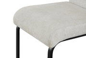 Nahaufnahme eines gepolsterten Sitzkissens in hellem Beige mit schwarzem Metallgestell, schräg von vorne/oben fotografiert