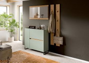 Modernes Flur-Set mit mintgrünem Sideboard auf schwarzem Metallgestell, Holz-Wandspiegel und Garderobenpaneelen mit Haken an grauer Wand, fotografiert in leichter Schrägansicht von vorn rechts.