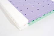 Meerlaagse schuimmatras met paarse geperforeerde toplaag, groene middenlaag en witte basis, gefotografeerd in schuin bovenaanzicht op witte achtergrond