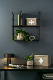 Aufbewahrungsbox MEDICINE in beige mit weißem Kreuz, auf einem Regal und Tisch in einem stilvollen Raum, seitliche Perspektive