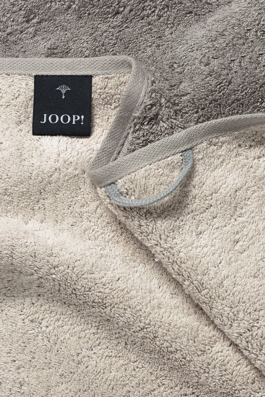 JOOP! Handtuch DOUBLEFACE CLASSIC Nahaufnahme eines beigen Handtuchs mit grauem Rand und einem schwarzen Etikett mit der Aufschrift 'JOOP!'