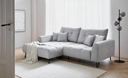 Graues Ecksofa mit Ottomane links, dekoriert mit Kissen und Decke, in einem hellen Wohnzimmer mit Holzboden und Stehlampe, seitliche Perspektive.