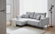 Graues Ecksofa mit Ottomane links, dekoriert mit Kissen und Decke, in einem hellen Wohnzimmer mit Holzboden und Stehlampe, seitliche Perspektive.