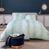 Bettwäsche-Set in sanftem Mintgrün mit geometrischem Muster, auf einem stilvoll eingerichteten Bett in einem modernen Schlafzimmer, frontal aufgenommen.