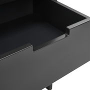 Nahaufnahme einer offenen Schublade einer schwarzen Nachtkonsole, Perspektive von oben.