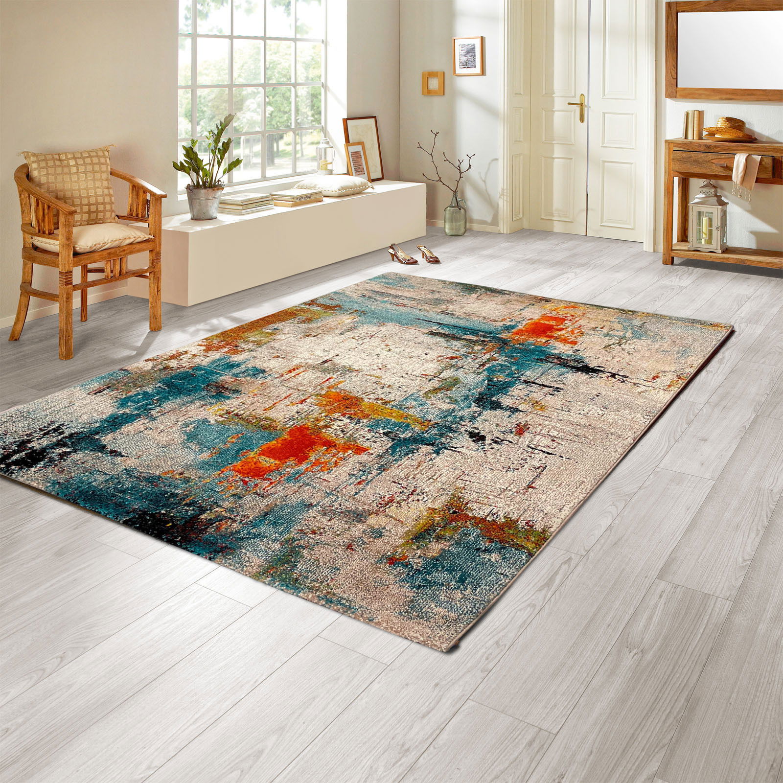 Merinos Webteppich BELIS Moderner Webteppich mit abstraktem Design in Blau-, Orange- und Beigetönen, auf hellem Holzboden in einem hellen Raum mit großen Fenstern und minimalistischer Einrichtung. Perspektive: schräg von oben.