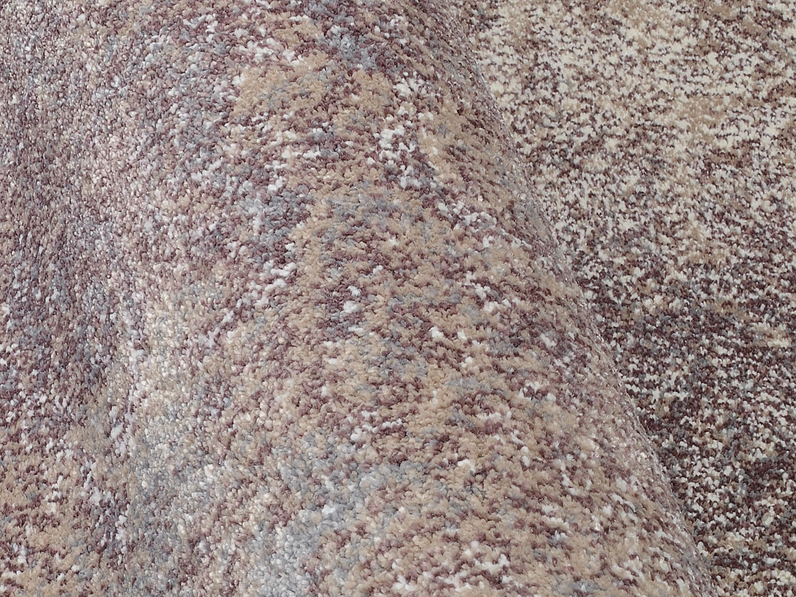 Nahaufnahme eines Designer Teppichs mit melierter Textur in Beige- und Grautönen, seitliche Perspektive