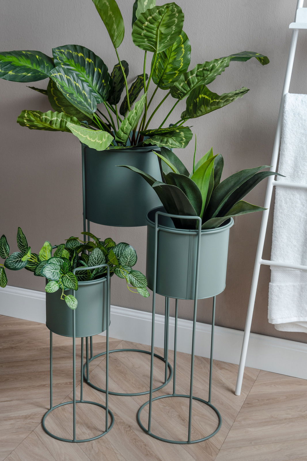 Dreiteiliges Pflanzgefäß-Set Essence in modernem Design, bestehend aus drei unterschiedlich hohen, grünen Metallständern mit Pflanzen, seitliche Perspektive.