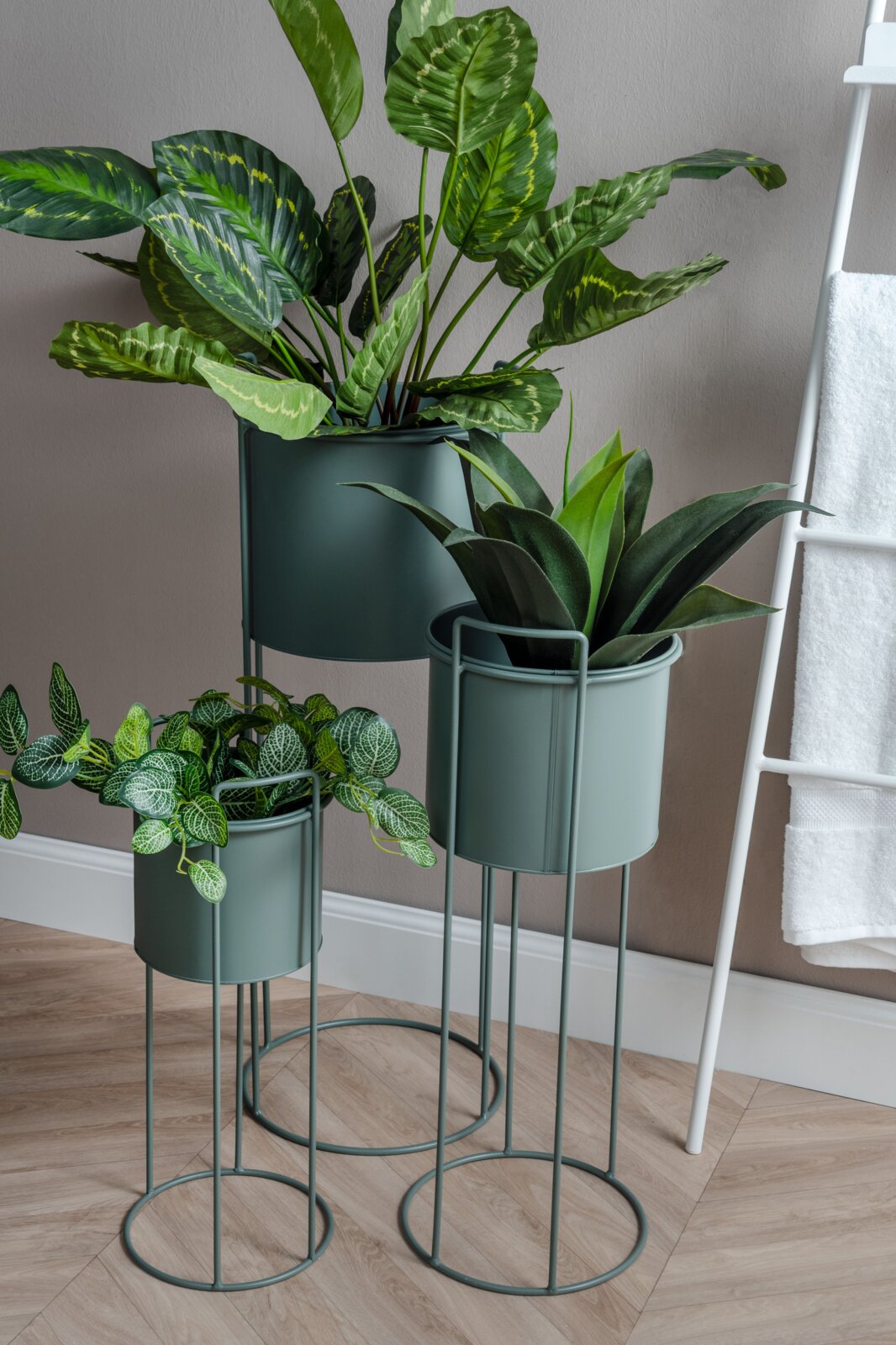 Dreiteiliges Pflanzgefäß-Set Essence in modernem Design, bestehend aus drei unterschiedlich hohen, grünen Metallständern mit Pflanzen, seitliche Perspektive.