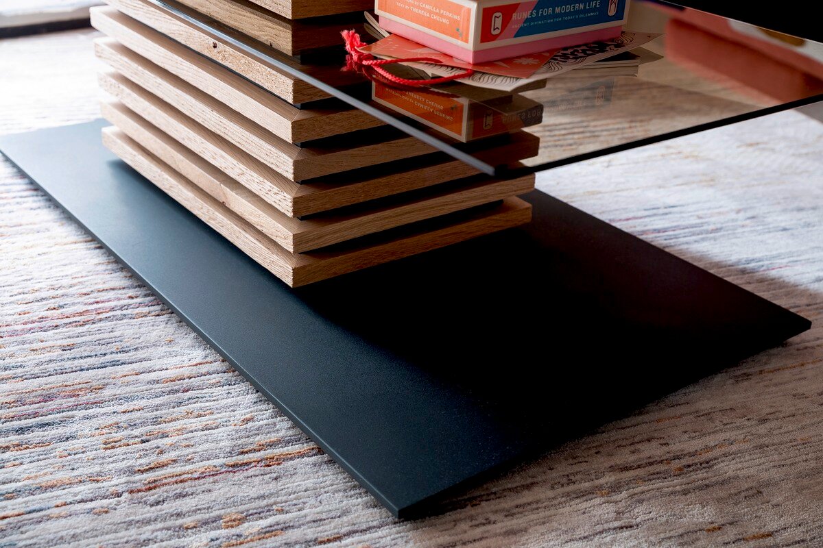 Moderner Couchtisch mit Glasplatte und gestapeltem Holzdesign, seitliche Perspektive