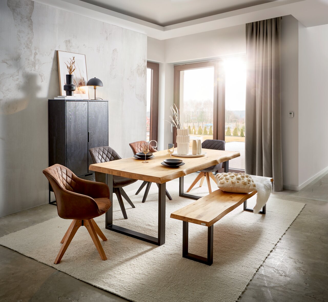 Landscape Esstisch COUNTRY II Modernes Esszimmer mit massivem Holztisch und passender Holzbank auf hellem Teppich, umgeben von gepolsterten Stühlen, seitliche Perspektive mit Blick auf große Fensterfront und Sonnenlicht