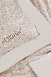 Nahaufnahme einer s.Oliver Satinbettwäsche in Beige mit dezentem Muster und Markenlogo, von oben fotografiert.