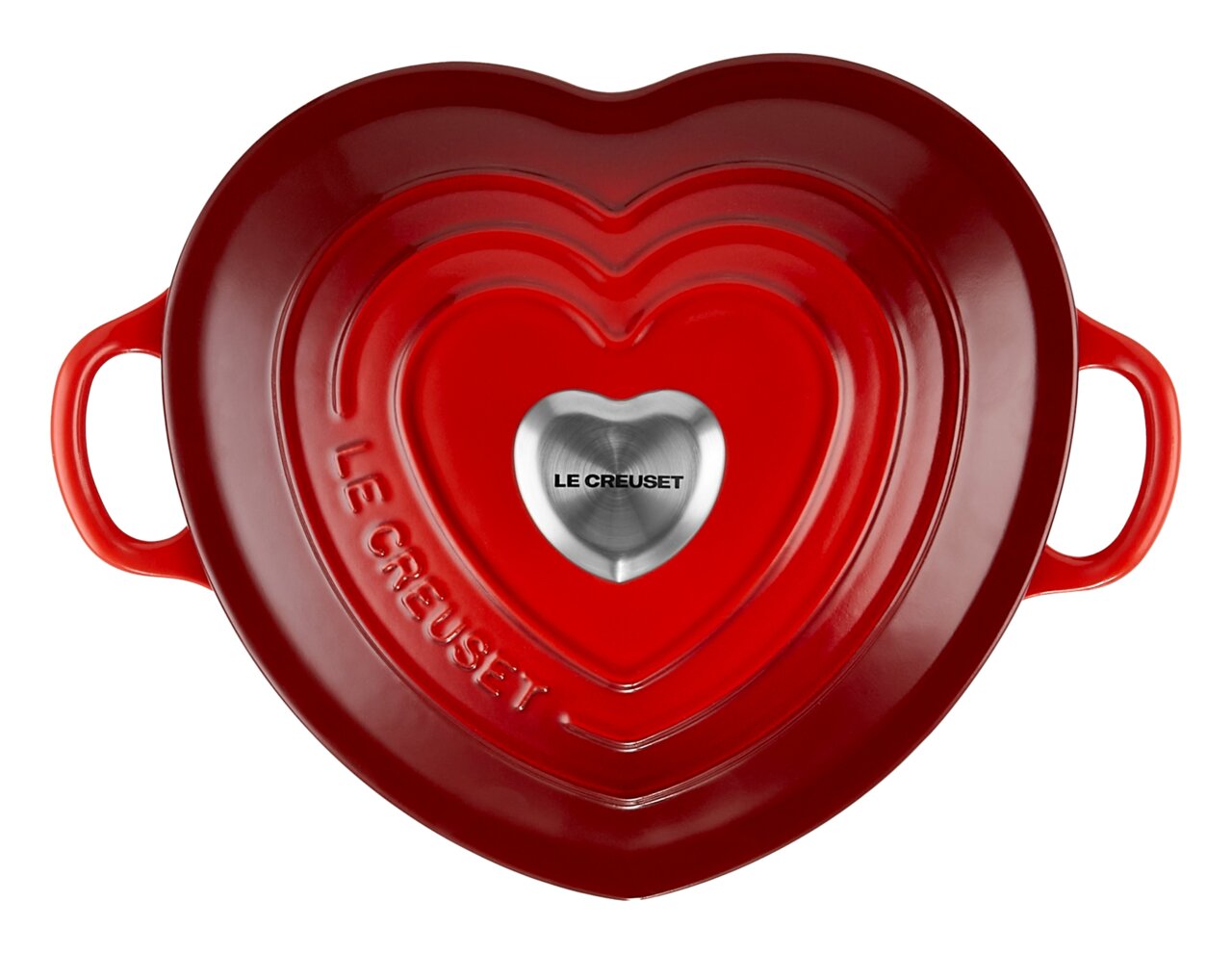 Herzförmiger, kirschroter Bräter von oben mit zwei Griffen und einem silbernen Knauf in der Mitte, Le Creuset-Logo sichtbar.