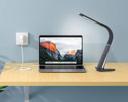 LED-Schreibtischleuchte in seitlicher Perspektive neben einem Laptop auf einem Holztisch.