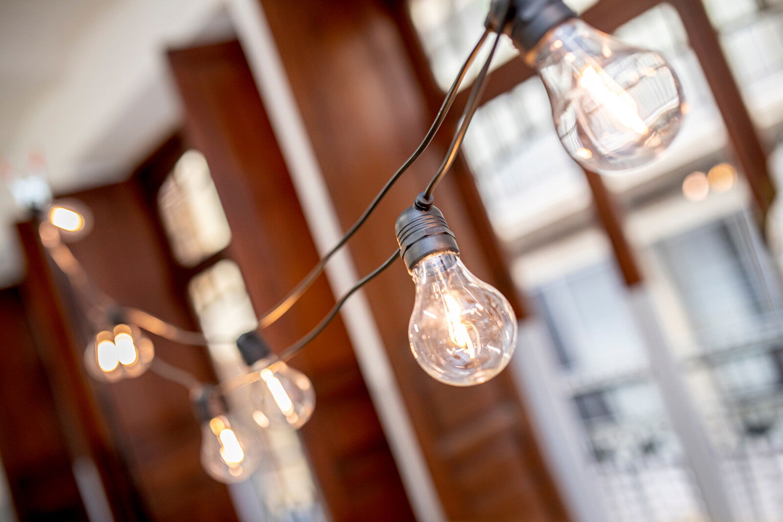 Nahaufnahme einer Lichterkette mit mehreren Glühbirnen in einem Innenraum, perspektivisch von der Seite aufgenommen.