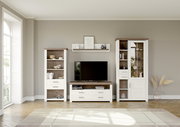 Modernes Wohnzimmer mit einem Wandboard über einem Fernseher, flankiert von zwei hohen Schränken. Perspektive von vorne.