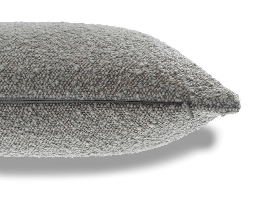 Nahaufnahme einer grauen Zierkissenhülle mit strukturierter Oberfläche und Reißverschluss, seitliche Perspektive
