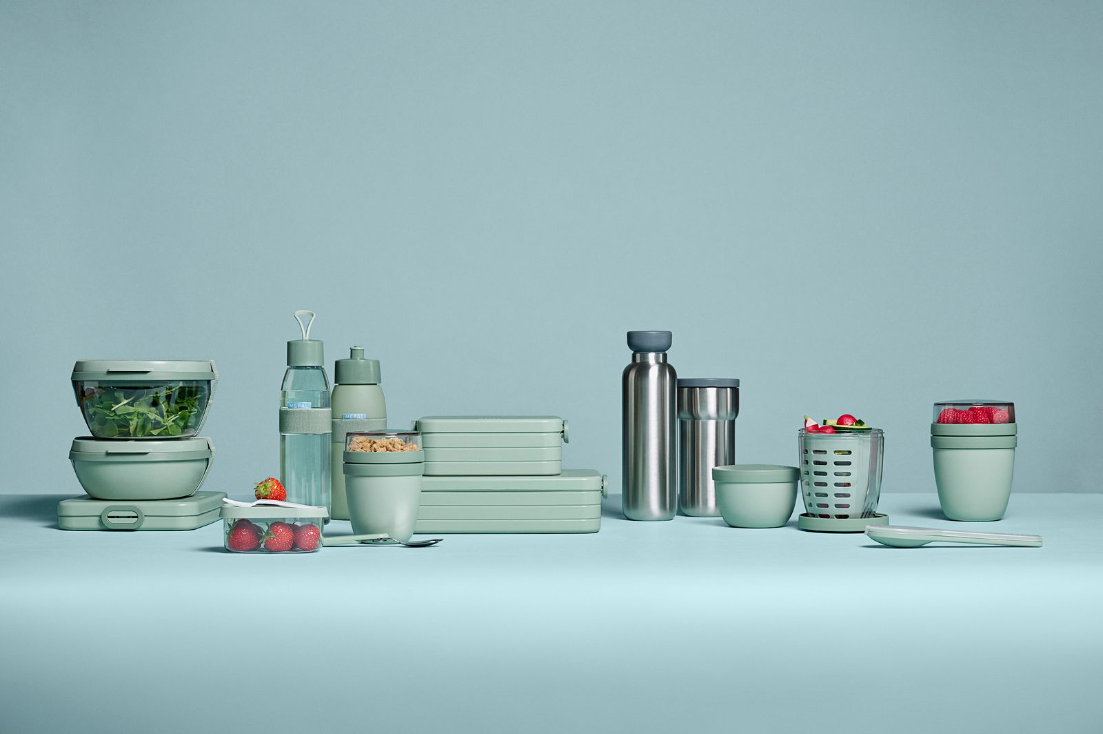 Mepal Fruitpot Nordic sage ELLIPSE Grüne Frischhalteboxen und Trinkflaschen in verschiedenen Größen und Formen, frontal auf einem hellgrünen Hintergrund präsentiert.